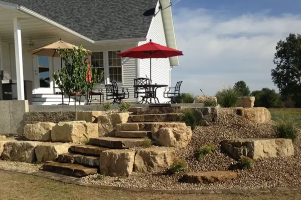 CanAm Professional Landscaping - gorgeous back patio with rock beds and stone steps, elevated platform with dining area - Girard, IL